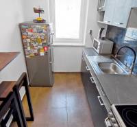 A kitchen in a 3-room apartment with tiles, a high table, and a fridge full of magnets.
