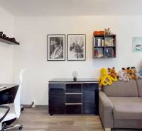 A room in a 3-room apartment with a shelf, a sofa, toys, and a desk.