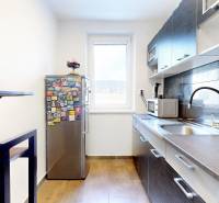 A kitchen in a 3-room apartment with a colorful refrigerator and dark kitchen tiles.