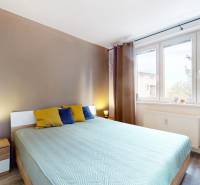 Bright bedroom in a 3-room apartment with wood-patterned flooring and large windows.