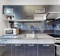 A kitchen in a 3-room apartment with a kitchen unit, a microwave, and decorated tiles with roses.