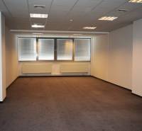 Office space with carpet and windows, illuminated by ceiling lights.