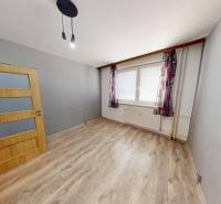 A room in a 3-room apartment with a wooden decor floor and curtains.