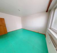 An empty room with a turquoise floor, white walls, and large windows in a 3-room apartment.