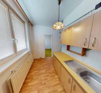 A kitchen in a 3-room apartment with a wooden decor floor and cabinets.