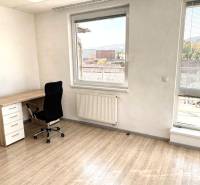 A workspace in a 2-room apartment with a wooden decor floor and a street view.