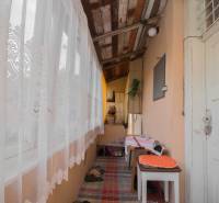 A balcony of a family house with a wooden ceiling, tables, and decorative curtains.