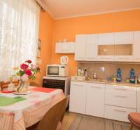 A kitchen in a family house with white furniture, a dining table, and flowers in a vase.