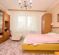 A bedroom in a family house with a carpet, furniture, a chandelier, and a painting.