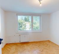 A bright room with wood-patterned flooring in a 4-room apartment, large windows with a view.