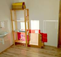An office with a shelf, a sink, and a wooden decor floor.