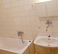 Bathroom with a bathtub, sink, and white tiles on the walls.