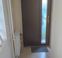 A narrow interior space with dark doors, tiles, and a radiator in an office.