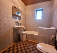 A bathroom in a family house with a bathtub, sink, and washing machine, checkered tiles.