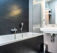 Bathroom with a shower bathtub and a sink in a 2-room apartment.