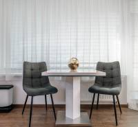 Dining area with two gray chairs and a table in a 2-room apartment.