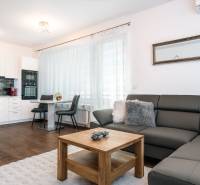 Living room with a kitchen in a two-room apartment with a wooden decor floor and a comfortable sofa.