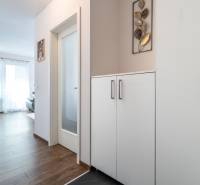 A hallway in a 2-room apartment with a wooden decor floor and a white wardrobe.