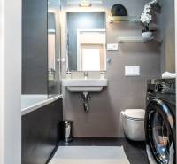 Elegant bathroom with a washing machine in a 2-room apartment, includes a bathtub and a sink.