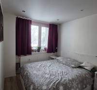 Bedroom in a 2-room apartment with a bed, nightstands, and curtains in dark colors.