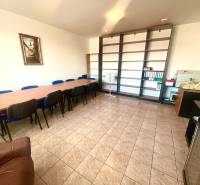 Offices with a long table, blue chairs and shelves, tiles.
