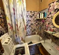 A bathroom with floral wallpaper, a washing machine, and a sink in a 3-room apartment.
