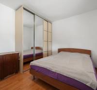 Bedroom in a family house with a bed, wardrobe, and floor with wood decor.