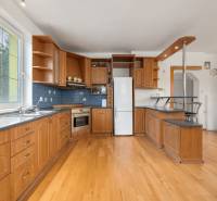 A kitchen in a family house with a wooden decor floor, wooden cabinets, and appliances.