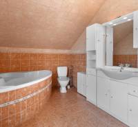 Bathroom in a family house with a bathtub, toilet, sink, and white furniture.