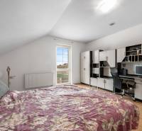 Bedroom in a family house with a wardrobe, a desk, and a floor with a wooden decor.