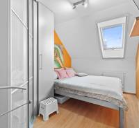 A small bedroom in a family house with a bed, a wardrobe, and colorful walls.