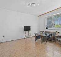 Living room in a family house with rattan seating and a television on a stand.