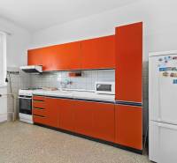 A kitchen in a family house with a stove, microwave, and orange cabinets.