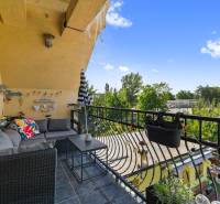 A family house balcony with comfortable seating, overlooking the garden and greenery.