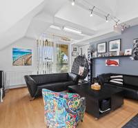 Living room in a family house with black sofas, a colorful armchair, and decorations on the walls.
