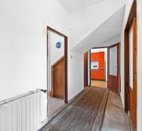 A hallway in a family house with doors leading to a kitchen with orange kitchen cabinets.