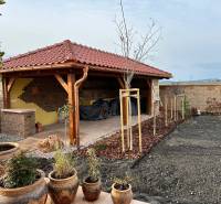 A family house in Bratislava - Jarovce with a garden gazebo and clay pots in the yard.