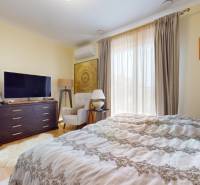 Bedroom with a TV, chair, and bed in a family house, with a wooden decor floor.