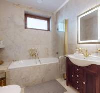 A bathroom in a family house with a bathtub, mirror, and wooden cabinet, in neutral tones.