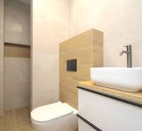 Bathroom in a family house with a sink, toilet, and tiles with a wooden decor.