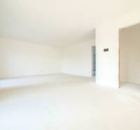 An empty room in a family house with white walls and a concrete floor.