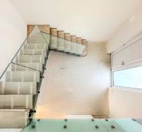 A staircase with glass railing in a family house with steps covered by protective foil.