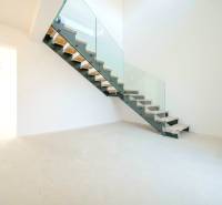 A staircase with glass railing in a family house and a floor with a wooden decor.