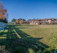 A residential plot in Veľká Lomnica with a lawn, fence, and views of the surrounding houses.