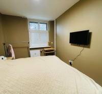 Bedroom in a 2-room apartment with a TV on the wall, a desk, and a hanging system.