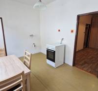 A kitchen with a gas stove, table, and chairs in a 3-room apartment.