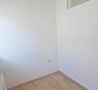 A small room in a 3-room apartment with a wood-patterned floor and a radiator.