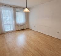 A spacious room with a wooden decor floor and curtains in a 3-room apartment.