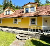 A family house in Vrbovce with a yellow facade, a red roof, and a front garden.