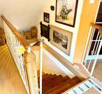 Interior staircase with decorative statues and paintings, floor with wooden decor.